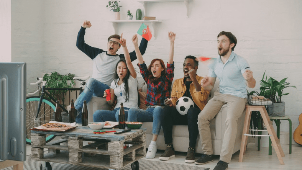 Sports fans watching a football match on television while different competitions use separate broadcasters.